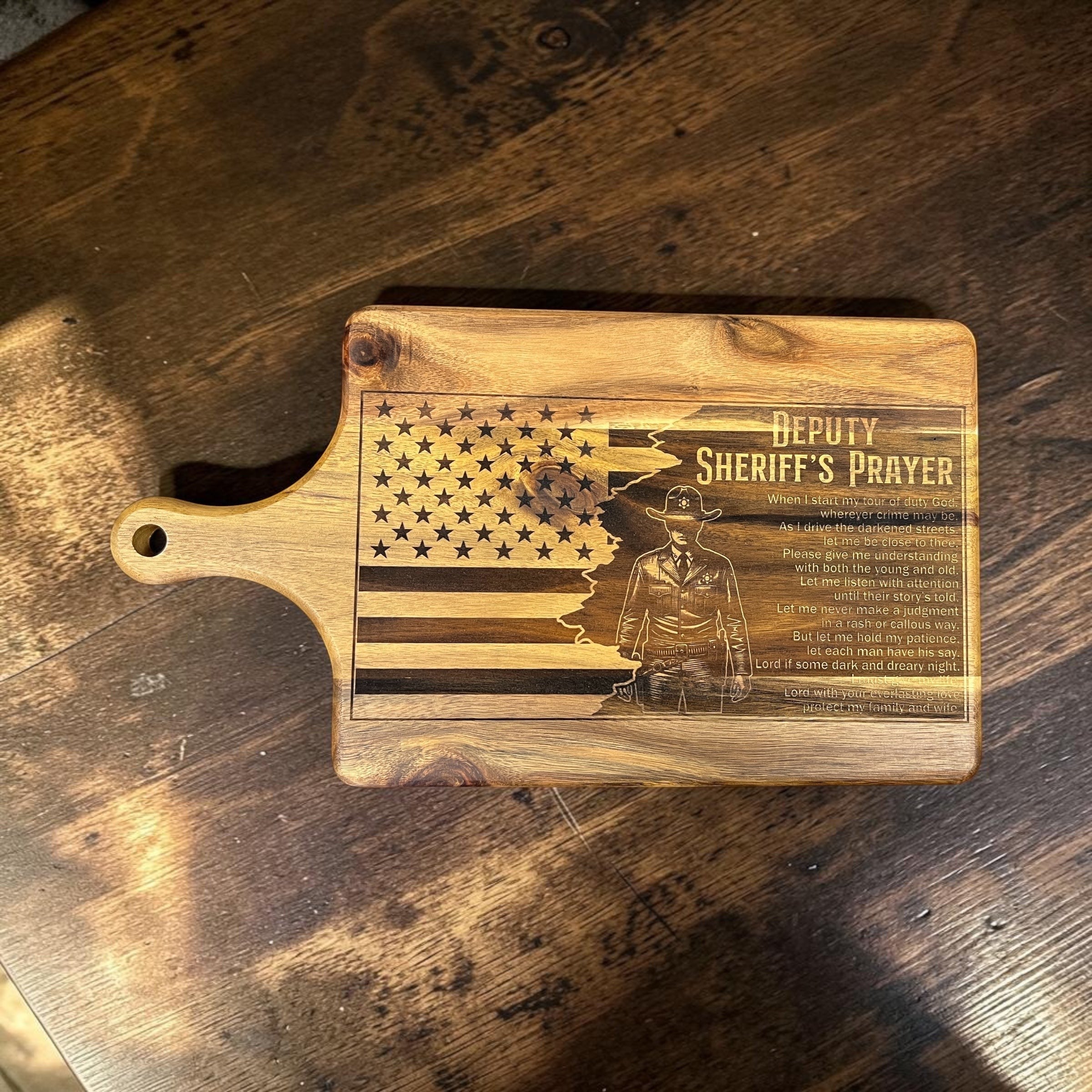 Show Me Custom Designs acacia wood cutting board with laser-engraved American flag, deputy silhouette, and prayer.